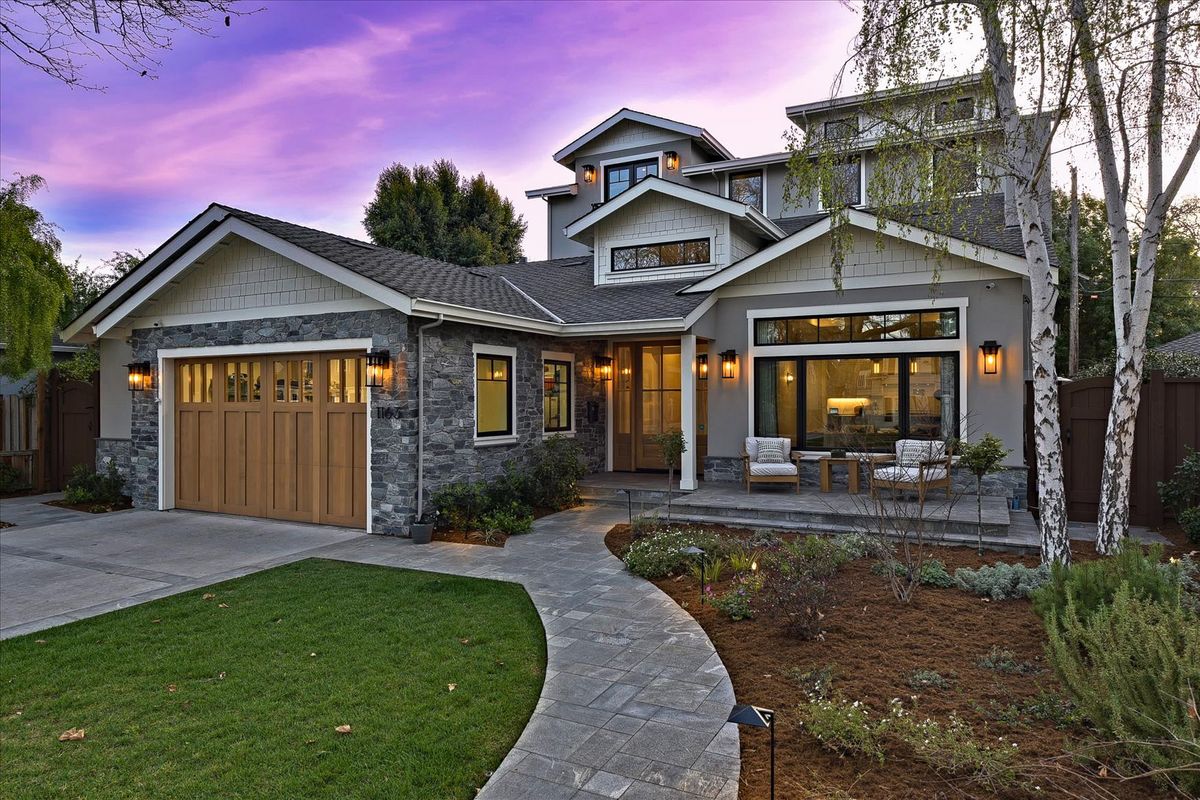 Luxury home exterior at dusk among oak trees